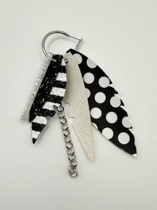 Black and white statement earrings with polka dot faux leather feather details, striped glitter accents, silver chain charm, and lightweight boutique design.