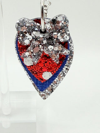 Layered patriotic statement earrings with silver glitter bow accent, silver glitter layer, royal blue textured faux leather, red glitter polka dot detail, and silver hoop closure.