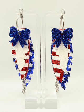 Patriotic red white and blue statement earrings with glitter star accents, layered faux leather feather details, silver chain charm, and lightweight boutique design.