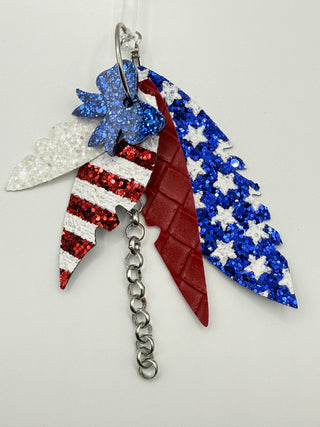 Patriotic red white and blue statement earrings with glitter star accents, layered faux leather feather details, silver chain charm, and lightweight boutique design.