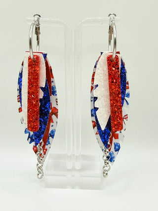Patriotic bow print statement earrings with red and blue glitter accents, layered faux leather feather details, silver chain charm, and lightweight boutique design.
