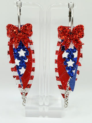 Patriotic red white and blue statement earrings with glitter stripes, star accents, layered faux leather feather details, silver chain charm, and lightweight boutique design.