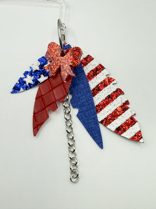 Patriotic red white and blue statement earrings with glitter stripes, star accents, layered faux leather feather details, silver chain charm, and lightweight boutique design.