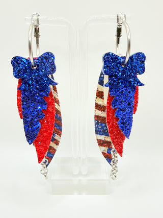 Red white and blue patriotic statement earrings with glitter bow accent, vintage Americana faux leather feather details, silver chain charm, and lightweight boutique design.