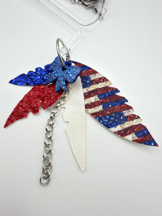 Red white and blue patriotic statement earrings with glitter bow accent, vintage Americana faux leather feather details, silver chain charm, and lightweight boutique design.