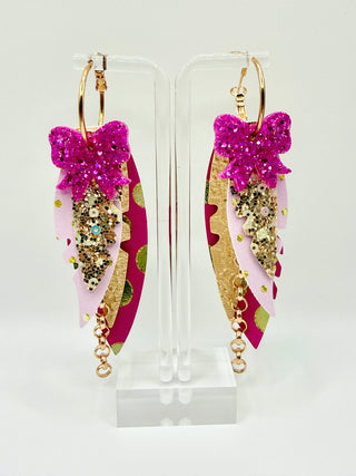 Pink and gold statement earrings with glitter bow accent, layered faux leather feather details, metallic polka dots, gold chain charm, and lightweight boutique design.