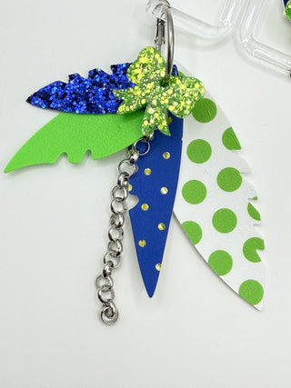 Layered blue and lime green statement earrings with glitter bow accent, polka dot faux leather feathers, silver chain detail, and lightweight boutique design.