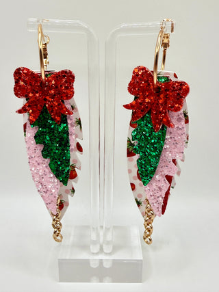 Layered strawberry print statement earrings with red glitter bow, pink sparkle accents, faux leather feather details, and rose gold chain charm.