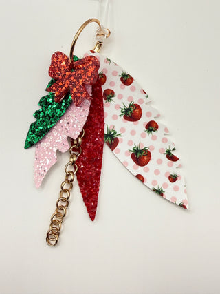 Layered strawberry print statement earrings with red glitter bow, pink sparkle accents, faux leather feather details, and rose gold chain charm.