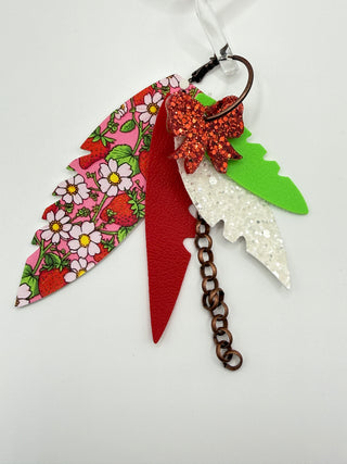 Red, pink, and green layered statement earrings with strawberry floral print, glitter bow accent, faux leather feather details, and bronze chain charm.