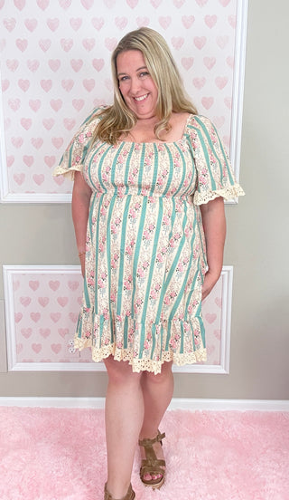 Woman wearing a floral dress with a striped pattern in a room with heart-shaped decorations on the wall.