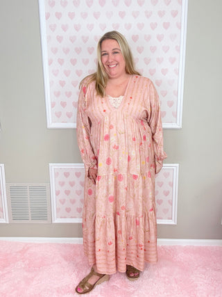 Woman wearing a pink polka dot dress standing in a room with pink walls and white frames.