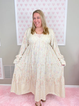 Woman wearing a white floral dress in a room with pink walls and a framed picture.