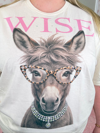 Person wearing a t-shirt with a donkey graphic and the word 'WISE' in pink.