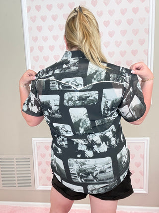 Person wearing a black and white patterned outfit in a room with pink walls and framed pictures.