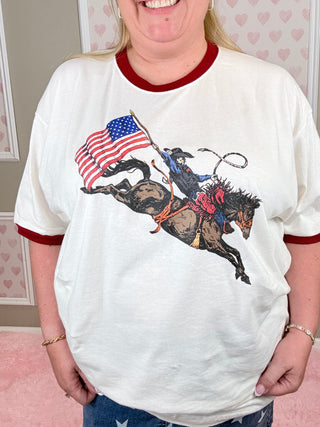 Person wearing a white shirt with a graphic design of a horse holding an American flag.