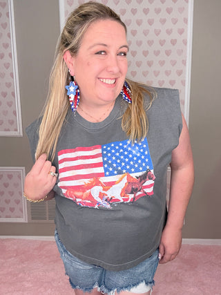 Person wearing a gray t-shirt with an American flag design, standing indoors.