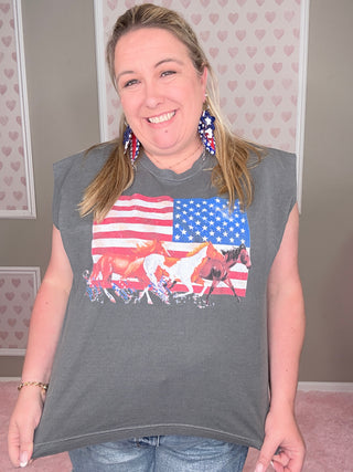 Person wearing a gray t-shirt with an American flag and graphic design, standing against a neutral background.