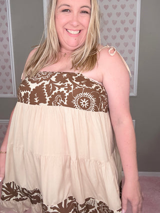 Woman wearing a strapless dress with brown floral patterns in a room with heart-shaped decorations on the wall.