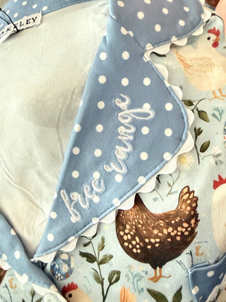 Pajama top with blue polka dot border and embroidered text on a floral background