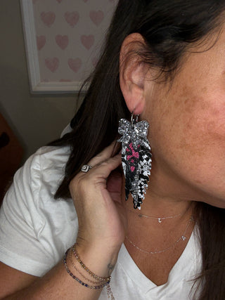 Person wearing a sparkling earring with a heart design, indoors.