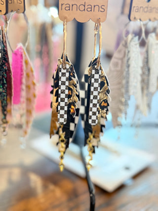 Black and white checkered faux leather earrings with layered gold metallic and leopard print accents, featuring gold chain dangles. Displayed on a “randans” card. Stylish, edgy, and race-inspired.