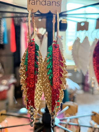 Decorative earrings with red, green, and gold colors on a stand.