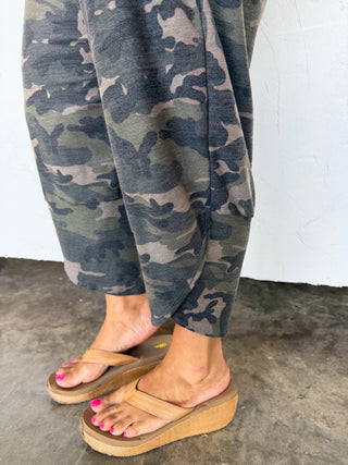 Person wearing camouflage pants and tan sandals on a concrete floor.