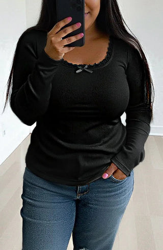 Person wearing a black long-sleeve top and blue jeans taking a mirror selfie.
