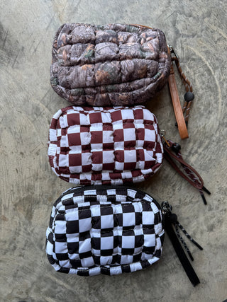 Small quilted puffer clutch with zipper closure and clip-on strap, designed to hold essentials like phone, keys, and cards — lightweight and sporty for everyday use.