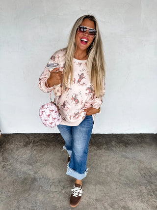 Woman wearing a floral top and jeans, holding a matching handbag against a white wall.