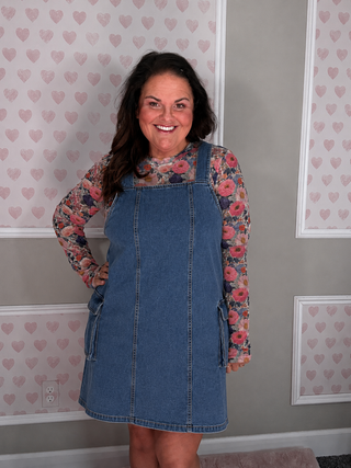 Stretchy denim overall dress with oversized pockets and relaxed fit, perfect for layering and everyday wear. 