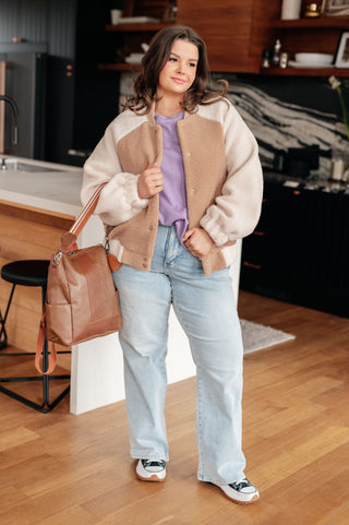 Woman holding a brown leather bag in a kitchen setting