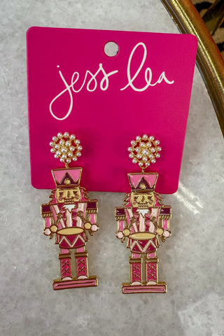 Pink nutcracker earrings on a branded card.