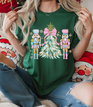 Person wearing a green t-shirt with Christmas-themed design featuring two nutcrackers and a tree.