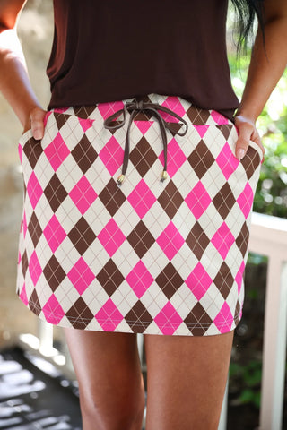 Women's preppy argyle skort in chocolate, cream, and pink featuring built-in shorts, stretchy waistband, adjustable drawstring, and functional side pockets for stylish fall outfits.