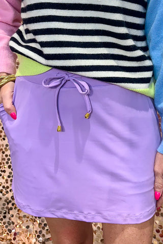 Solid purple skort with built-in shorts, elastic back waistband, drawstring waist, and side pockets, styled for casual spring and summer wear.