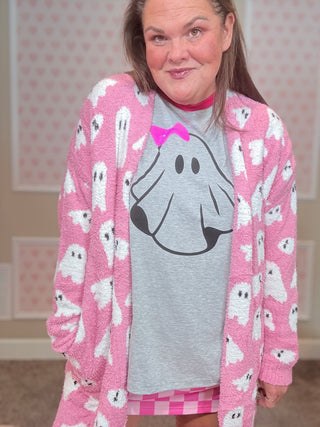 Person wearing a pink cardigan with ghost patterns and a gray shirt with a dog graphic.