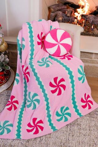 Pink blanket with candy cane pattern draped over a chair in a cozy living room.