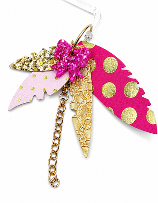 A decorative earring featuring three stylized feathers in pink, gold, and magenta, with a glittery pink bow and a dangling gold chain on a white background.