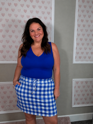 Royal blue sleeveless bodysuit with blue and white gingham skort, chic boutique style