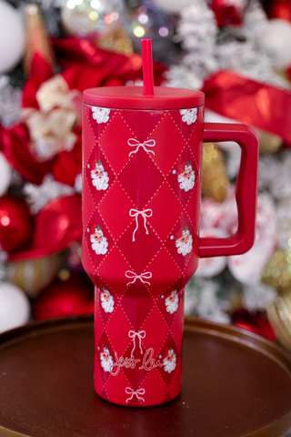 Red Christmas-themed tumbler with a pattern of snowmen and bows on a decorative background.