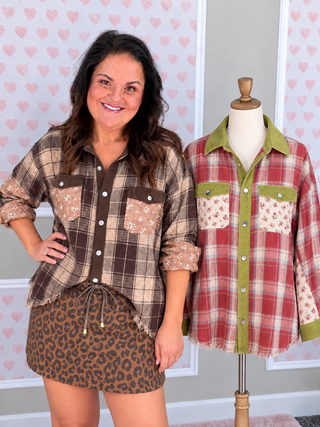 A woman stands next to a mannequin wearing a plaid button-up shirt with patterned pocket details and a leopard-print mini skirt. The background features a light gray wall with pink heart patterns.