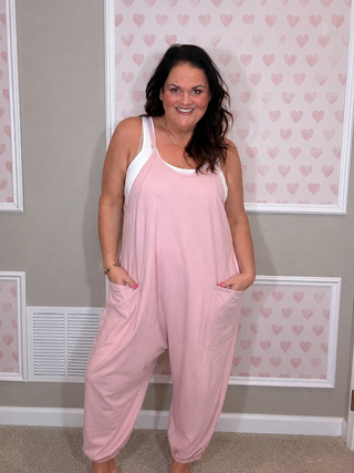 Plus size model wearing the Scottie oversized blush pink romper in washed cotton with front pockets and elastic ankle cuffs.