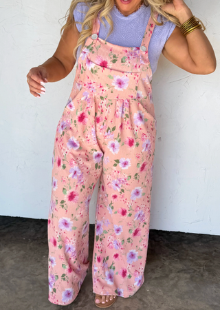 Woman wearing a floral jumpsuit against a white wall