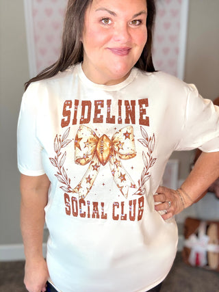 Person wearing a white t-shirt with 'Sideline Social Club' design