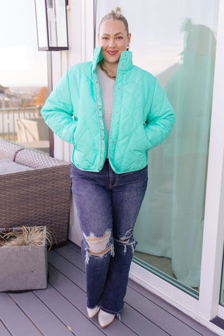Person wearing a turquoise puffer jacket on a balcony