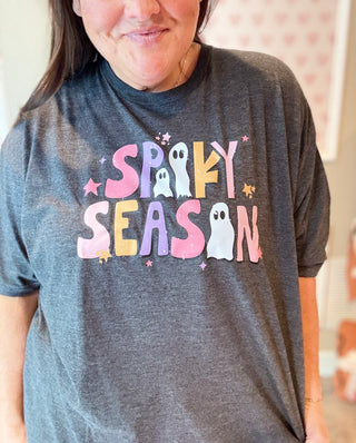 Person wearing a gray t-shirt with 'Spooky Season' text and ghost graphics.