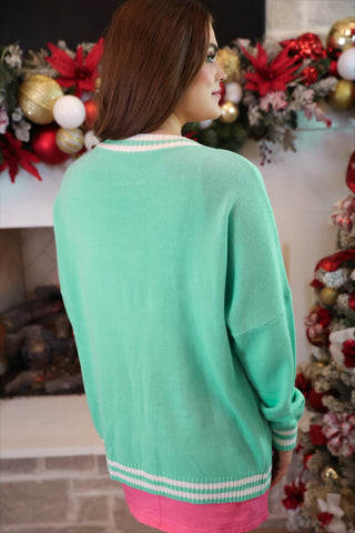 Woman wearing a green sweater with a festive background