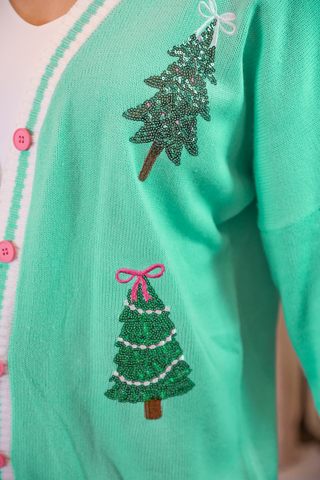 Green cardigan with beaded Christmas tree designs on a blurred background